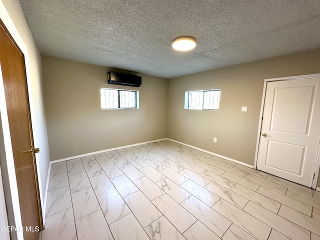45 S Boone St, El Paso, TX 79905 - unfurnished room with a wall mounted air conditioner, a textured ceiling, marble finish floor, and baseboards