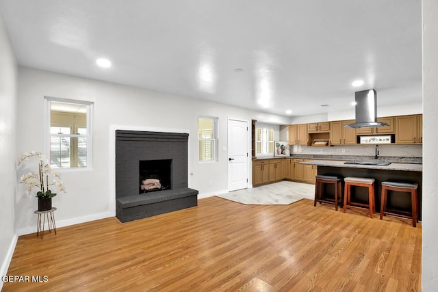 2801 Brady Pl, El Paso, TX 79935 - kitchen with baseboards, light countertops, light wood-style flooring, and island exhaust hood