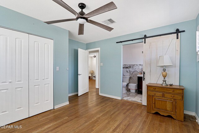 4731 Leeds Ave, El Paso, TX 79903 - bedroom with a closet, wood finished floors, a barn door, visible vents, and baseboards
