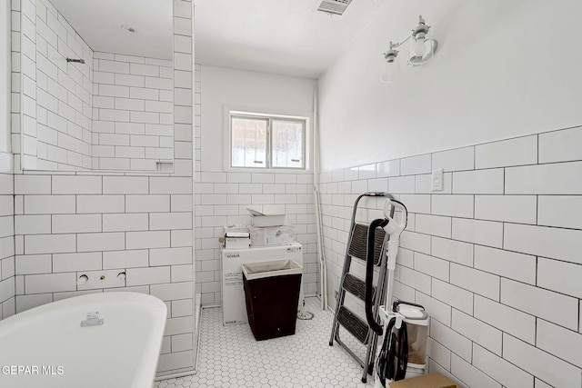 4731 Leeds Ave, El Paso, TX 79903 - full bath with tile walls, visible vents, tile patterned floors, a freestanding bath, and a wainscoted wall