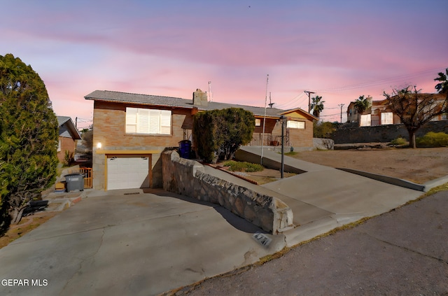 4731 Leeds Ave, El Paso, TX 79903 - ranch-style home with concrete driveway, an attached garage, a chimney, and brick siding