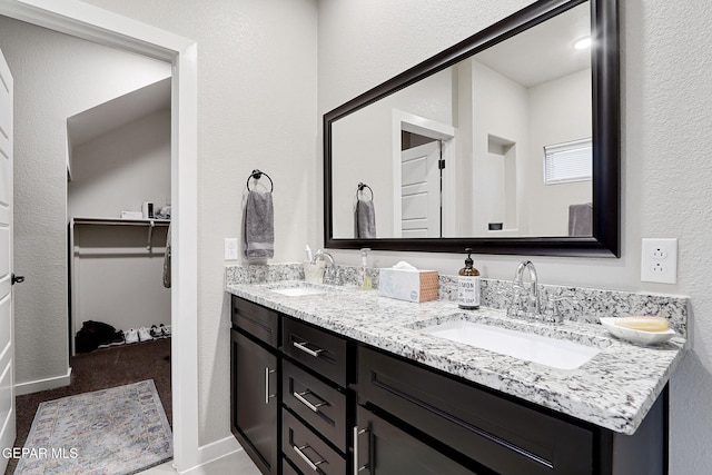 7809 Enchanted Circle Dr, El Paso, TX 79911 - bathroom with double vanity, a walk in closet, and a textured wall