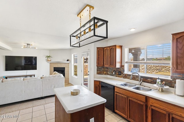 kitchen with a sink, dishwasher, a center island, light tile patterned floors, and light countertops