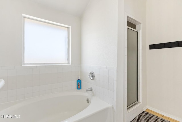bathroom featuring a shower stall, a bath, tile patterned floors, and baseboards