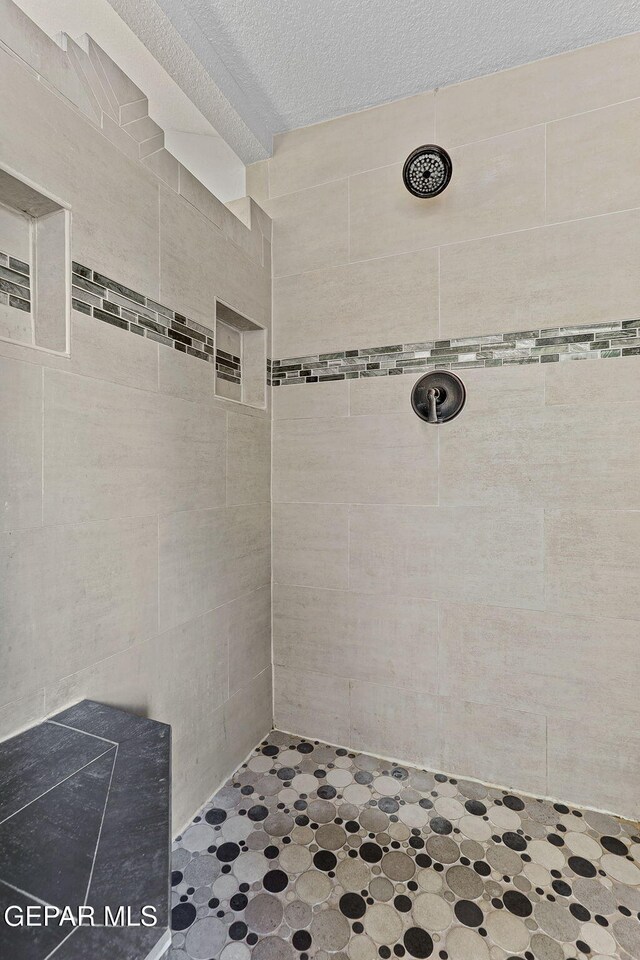 2250 Nancy Mcdonald Dr, El Paso, TX 79936 - bathroom featuring a tile shower, tile walls, and a textured ceiling