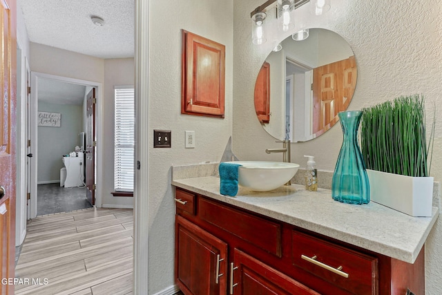 2250 Nancy Mcdonald Dr, El Paso, TX 79936 - bathroom featuring a textured wall, vanity, wood finished floors, a textured ceiling, and baseboards