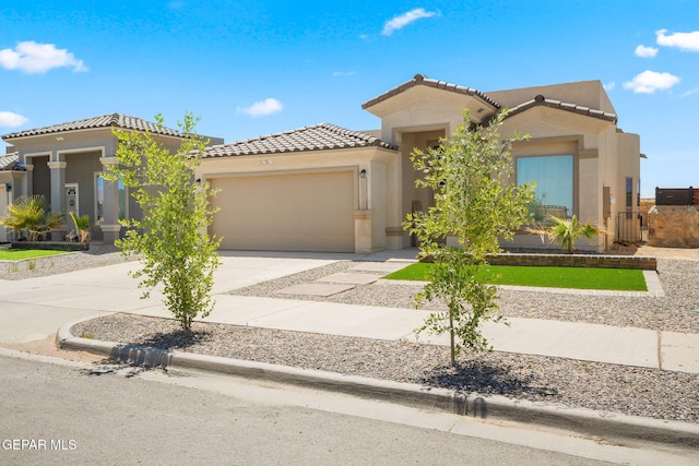 mediterranean / spanish home featuring an attached garage, a tiled roof, stucco siding, and driveway