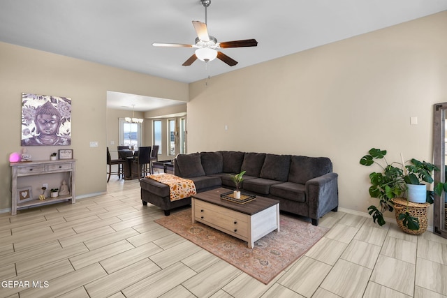 living area featuring wood finish floors, ceiling fan with notable chandelier, and baseboards