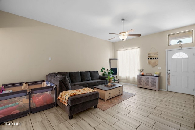 living room featuring a ceiling fan, baseboards, and wood tiled floor