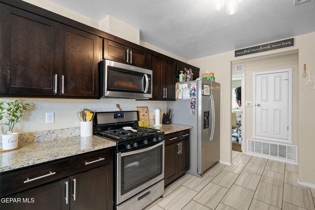 kitchen featuring stainless steel appliances, visible vents, dark brown cabinetry, and decorative backsplash