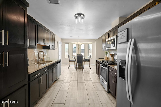 kitchen with a sink, stainless steel appliances, visible vents, a chandelier, and backsplash