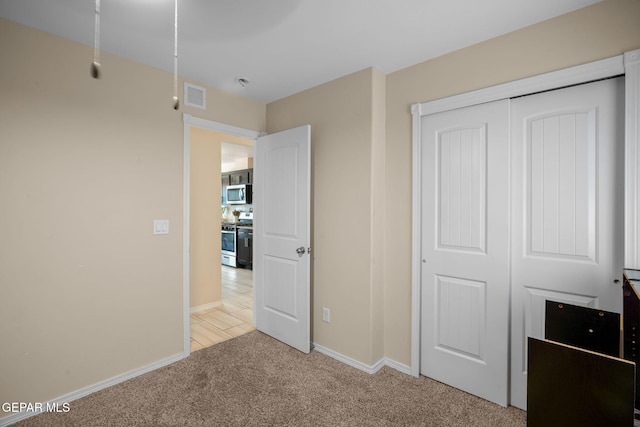 unfurnished bedroom featuring baseboards, light carpet, a closet, and visible vents