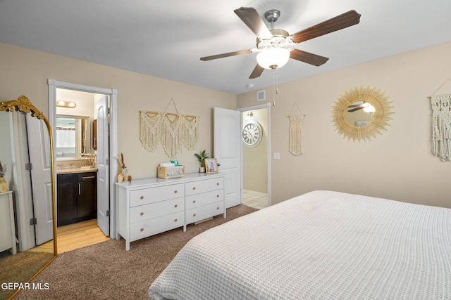 bedroom featuring ensuite bath, light carpet, and a ceiling fan