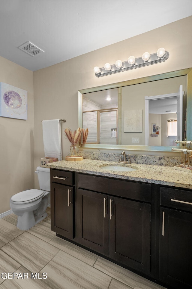 bathroom with vanity, toilet, visible vents, and a shower stall