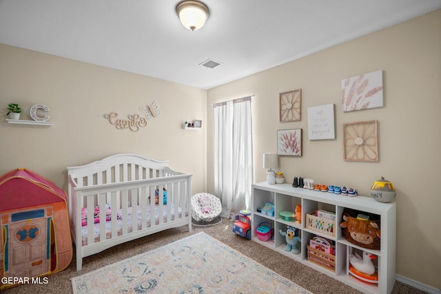 bedroom with a crib, visible vents, and carpet floors