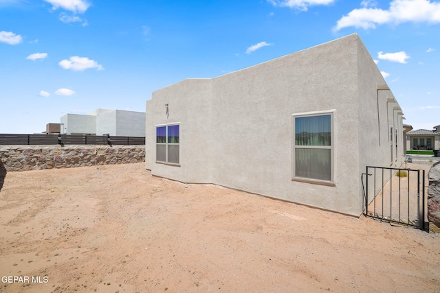 back of house featuring stucco siding and fence
