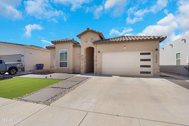 mediterranean / spanish home featuring stucco siding, concrete driveway, a garage, and stone siding