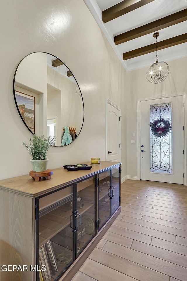 entrance foyer with light wood-type flooring, beam ceiling, and beverage cooler