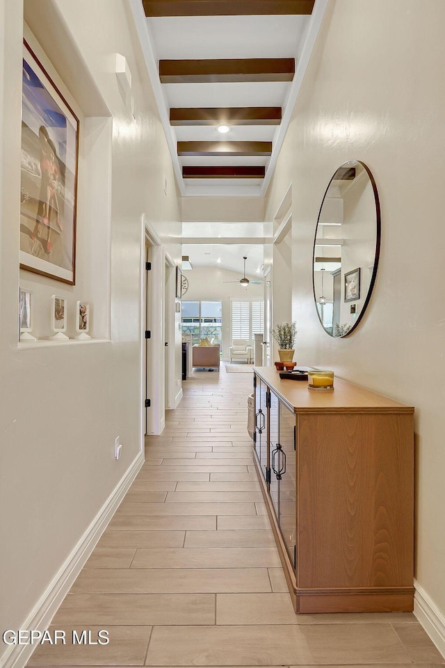 corridor with baseboards, light wood finished floors, and beam ceiling