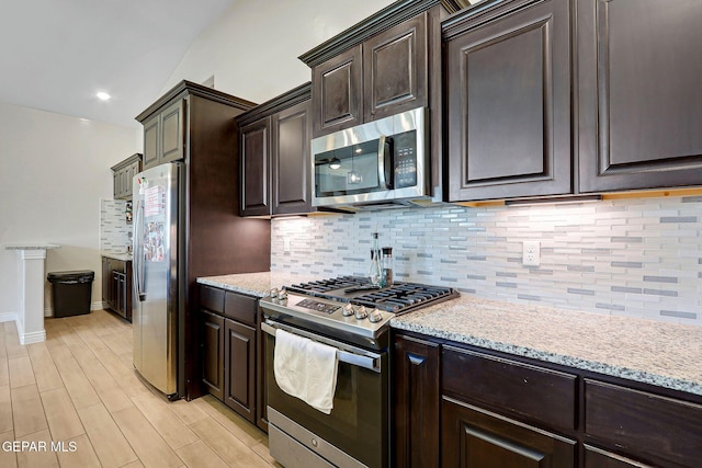 kitchen featuring stainless steel appliances, tasteful backsplash, dark brown cabinetry, light stone counters, and recessed lighting