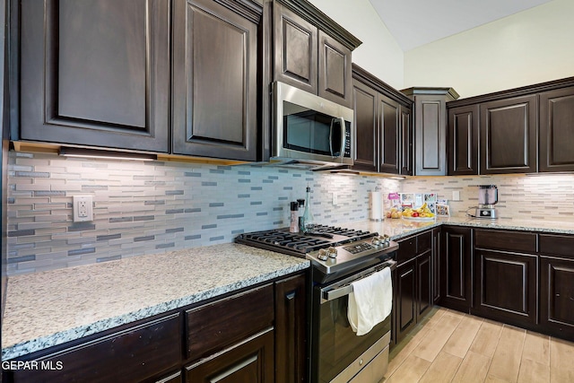 kitchen featuring appliances with stainless steel finishes, tasteful backsplash, light stone counters, and light wood-style flooring