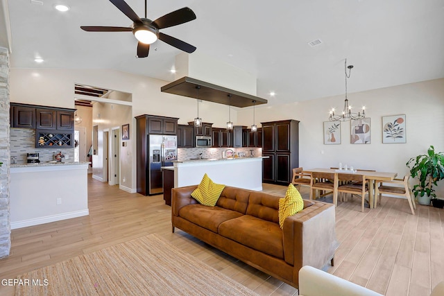living room featuring ceiling fan, lofted ceiling, light wood-style flooring, a chandelier, and recessed lighting