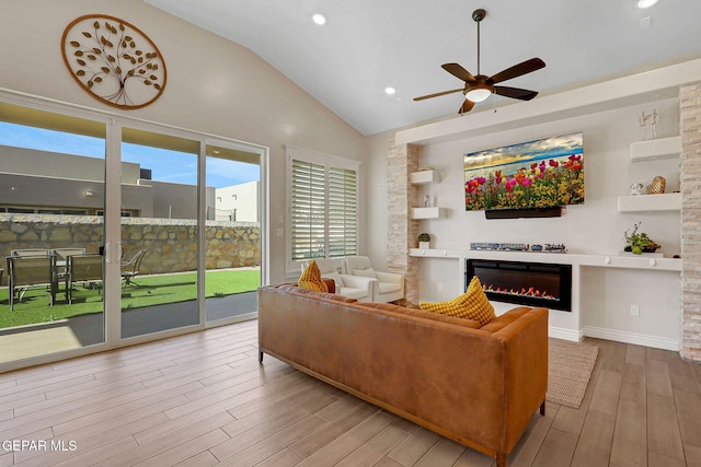 living room featuring lofted ceiling, a glass covered fireplace, wood finished floors, a ceiling fan, and recessed lighting