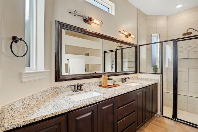 bathroom featuring a shower stall, wood finished floors, and double vanity