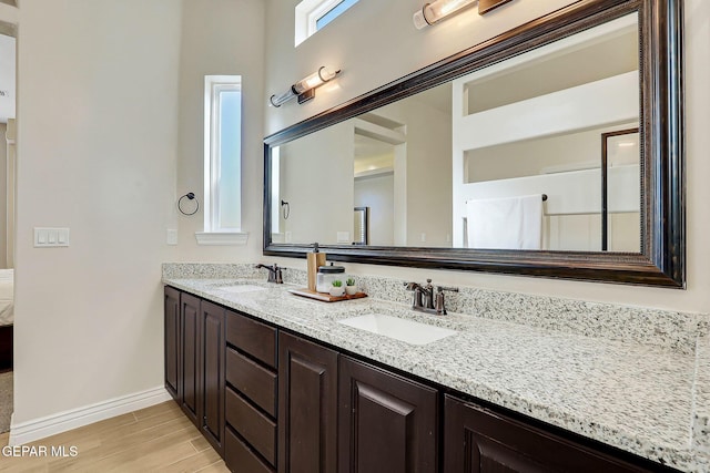 bathroom with wood finished floors, baseboards, and double vanity
