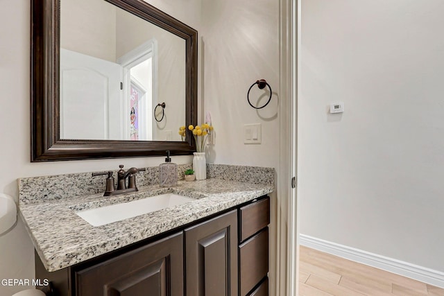 bathroom featuring vanity, baseboards, and wood finished floors
