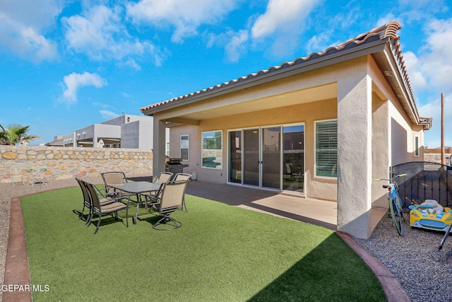 rear view of house with stucco siding, a patio area, and a tiled roof