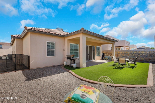 rear view of house with a tile roof, stucco siding, a patio area, and a gate