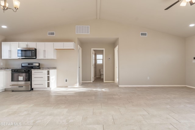 kitchen with stainless steel microwave, range with gas stovetop, lofted ceiling, white cabinetry, and a ceiling fan