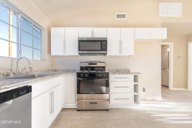 kitchen featuring stainless steel appliances, a sink, white cabinetry, light stone counters, and light tile patterned flooring
