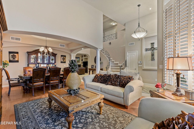 6225 Via Serena Dr, El Paso, TX 79912 - living room featuring arched walkways, wood finished floors, ornate columns, stairway, and a towering ceiling
