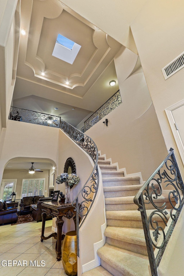 6225 Via Serena Dr, El Paso, TX 79912 - staircase featuring arched walkways, a high ceiling, tile patterned floors, and a skylight