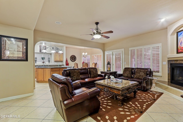 6225 Via Serena Dr, El Paso, TX 79912 - living room featuring light tile patterned flooring, a glass covered fireplace, a ceiling fan, baseboards, and a chandelier