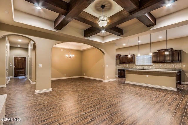 unfurnished living room with coffered ceiling, dark wood finished floors, arched walkways, and recessed lighting