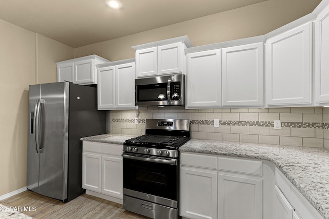 7541 Wolf Creek Dr, El Paso, TX 79911 - kitchen with stainless steel appliances, light wood-type flooring, white cabinetry, and tasteful backsplash