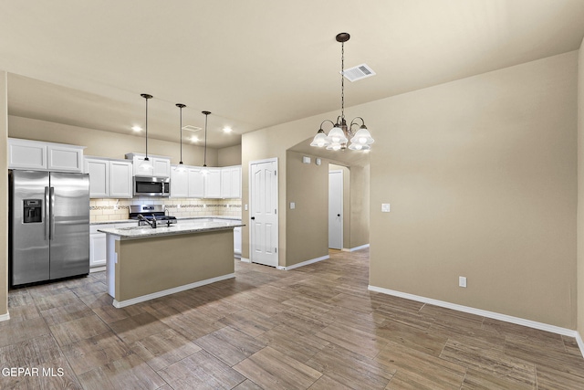 7541 Wolf Creek Dr, El Paso, TX 79911 - kitchen with appliances with stainless steel finishes, a sink, tasteful backsplash, white cabinets, and a kitchen island with sink
