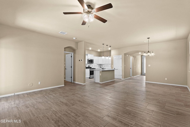 7541 Wolf Creek Dr, El Paso, TX 79911 - unfurnished living room featuring arched walkways, ceiling fan, wood finish floors, and a chandelier