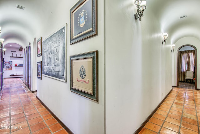 hall with arched walkways, tile patterned flooring, and baseboards