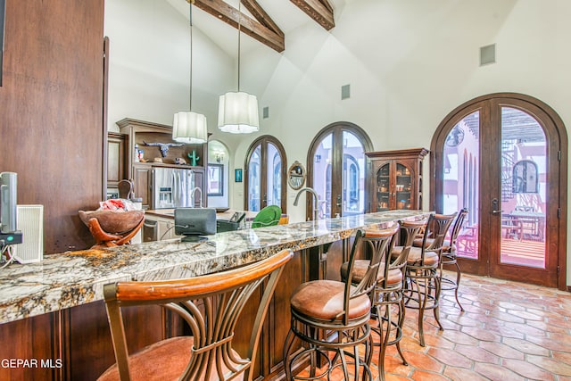 bar area with high vaulted ceiling, beamed ceiling, stainless steel refrigerator with ice dispenser, french doors, and pendant lighting