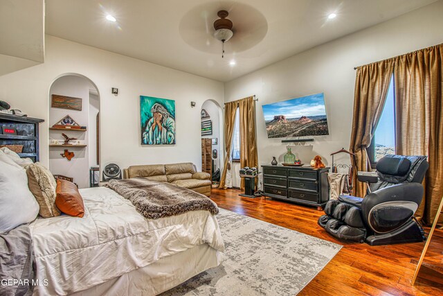 bedroom with arched walkways, wood finished floors, recessed lighting, and ceiling fan