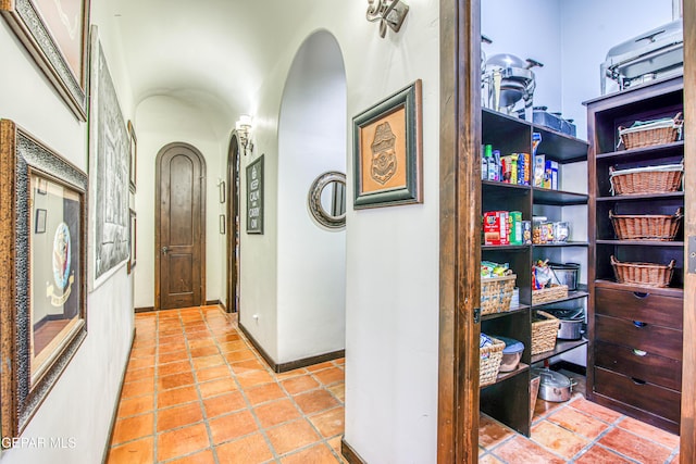 hall featuring arched walkways and baseboards