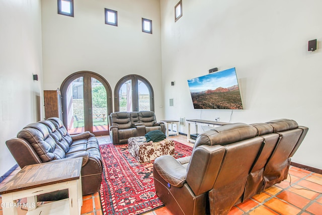 living room featuring a towering ceiling, healthy amount of natural light, baseboards, french doors, and light tile patterned floors