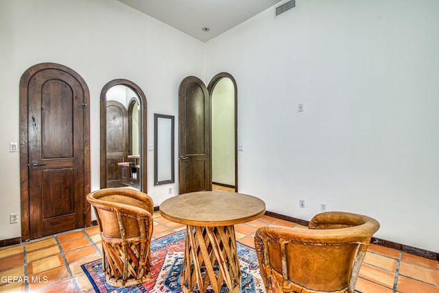 dining area featuring arched walkways, baseboards, and light tile patterned floors