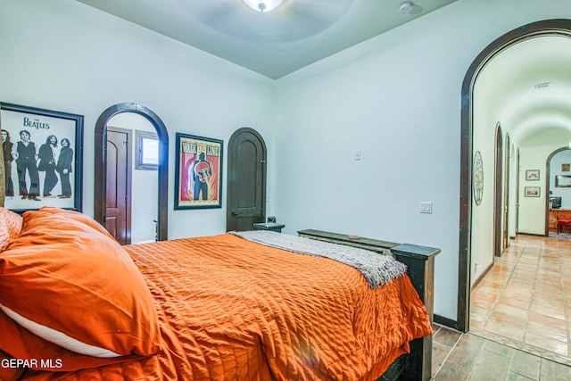 bedroom featuring arched walkways, wood finished floors, and ceiling fan