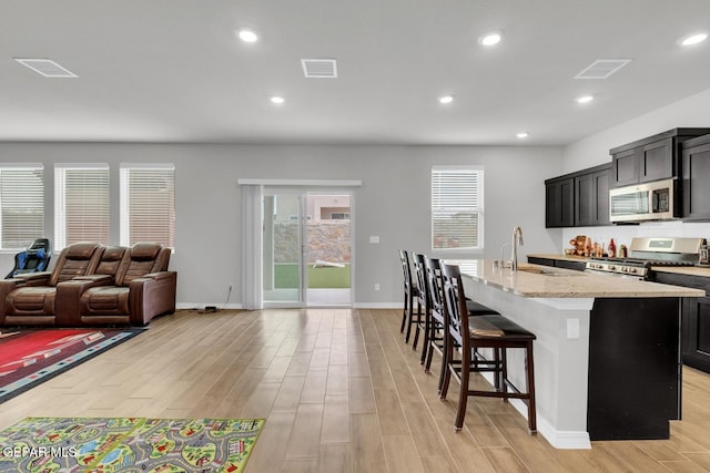 13868 Sky Ranger Ave, El Paso, TX 79928 - kitchen with stainless steel appliances, a sink, light wood-style flooring, a center island with sink, and recessed lighting