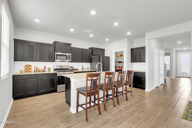 13868 Sky Ranger Ave, El Paso, TX 79928 - kitchen featuring stainless steel appliances, a center island with sink, baseboards, light wood-style floors, and recessed lighting